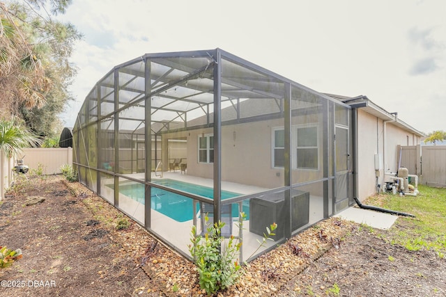 view of swimming pool featuring a patio area, glass enclosure, a fenced backyard, and a fenced in pool