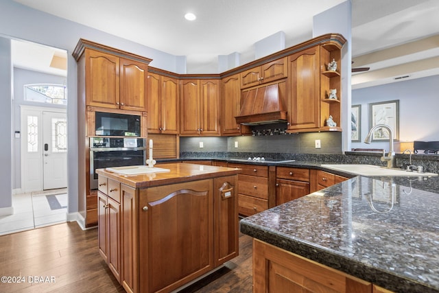 kitchen with dark hardwood / wood-style flooring, premium range hood, oven, and sink