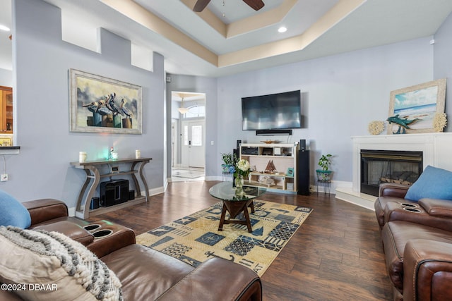 living room featuring a tray ceiling, ceiling fan, and dark wood-type flooring