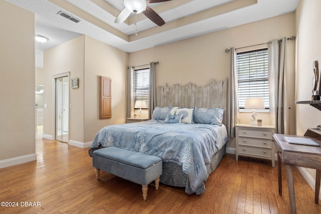 bedroom featuring ceiling fan, a raised ceiling, and light hardwood / wood-style flooring