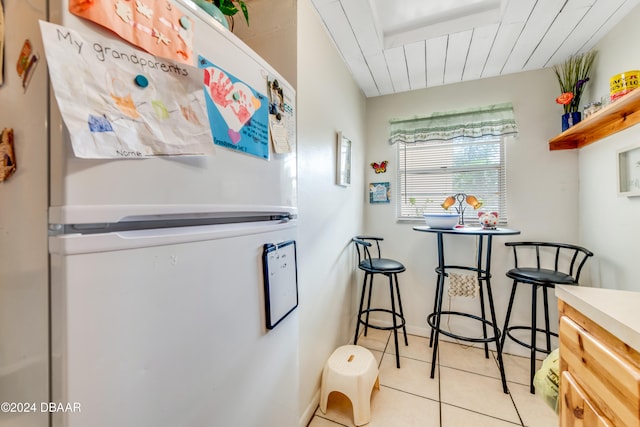 kitchen with light tile patterned floors and white refrigerator