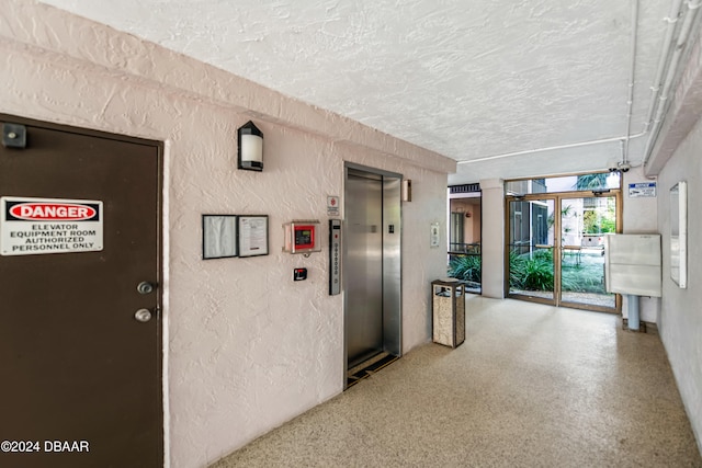 corridor with a textured ceiling and elevator