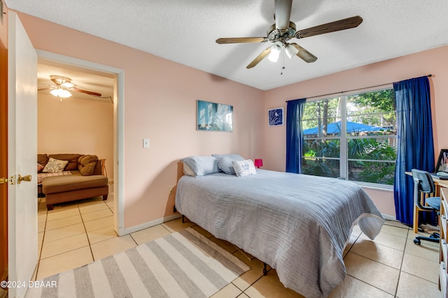 bedroom featuring ceiling fan, light tile patterned flooring, and a textured ceiling