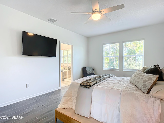 bedroom featuring a textured ceiling, hardwood / wood-style flooring, ensuite bath, and ceiling fan