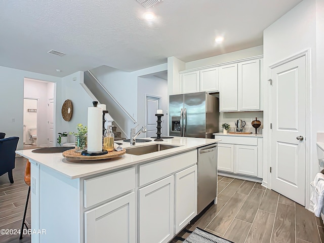 kitchen with white cabinets, appliances with stainless steel finishes, sink, and an island with sink