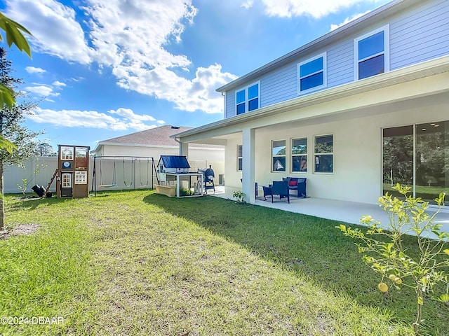 back of house with a lawn, a patio area, and a playground