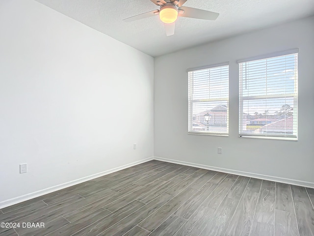 spare room featuring ceiling fan, dark wood-type flooring, and a textured ceiling