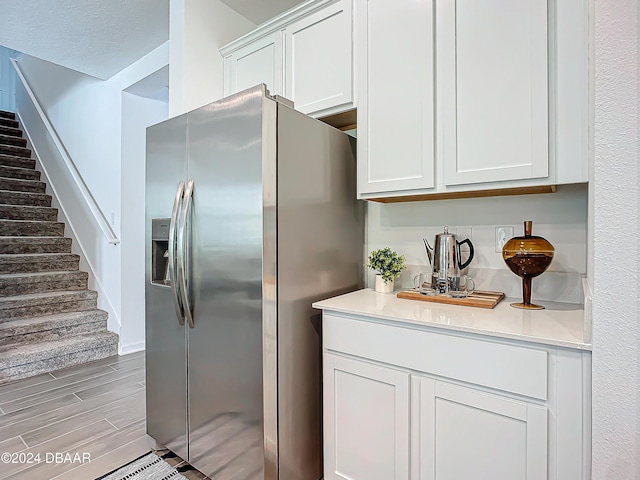 kitchen with stainless steel fridge, light hardwood / wood-style flooring, and white cabinetry