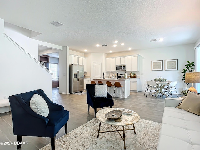 living room featuring light wood-type flooring and a textured ceiling