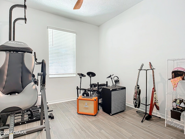 exercise area with ceiling fan and a textured ceiling