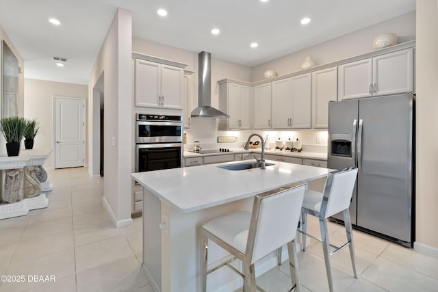 kitchen featuring stainless steel appliances, light countertops, visible vents, wall chimney range hood, and a sink