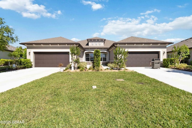 prairie-style home with stucco siding, driveway, a front yard, and a garage