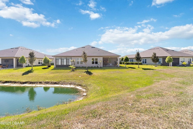 back of property featuring a sunroom, a yard, and a water view