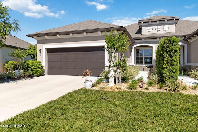 prairie-style house featuring a garage, concrete driveway, a front yard, and stucco siding