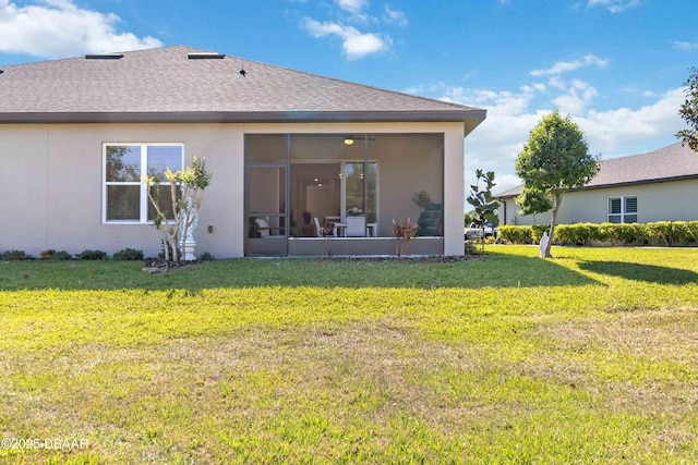 back of house with stucco siding, a sunroom, a yard, and a shingled roof