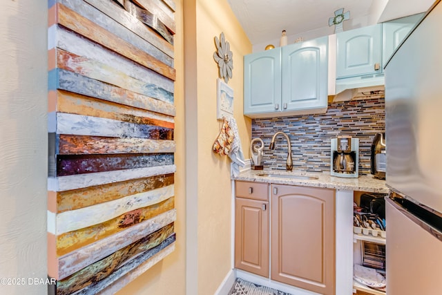 interior space with tasteful backsplash, a sink, and freestanding refrigerator