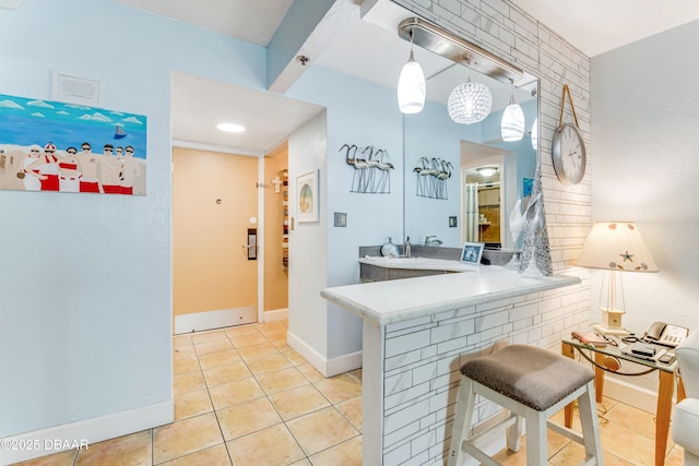 interior space featuring light tile patterned floors, light countertops, a peninsula, and decorative light fixtures