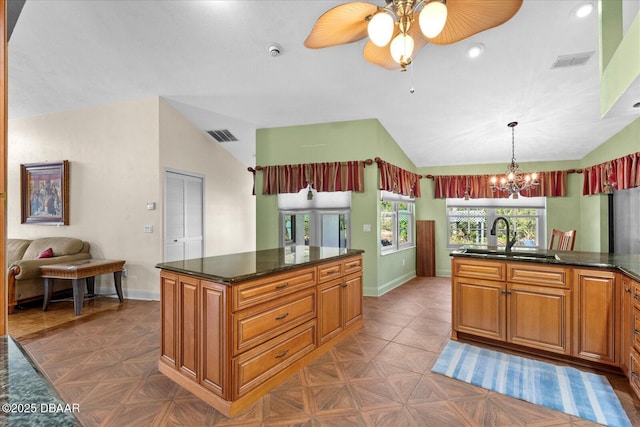 kitchen featuring ceiling fan with notable chandelier, vaulted ceiling, baseboards, and a sink