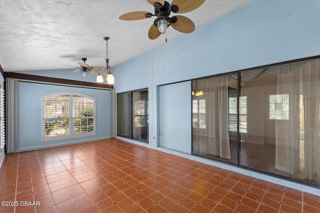 empty room featuring lofted ceiling and ceiling fan with notable chandelier