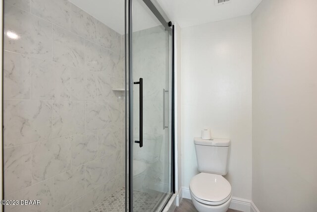 bathroom with toilet and a shower with shower door