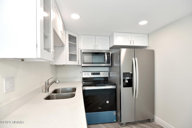 kitchen with white cabinetry, stainless steel appliances, sink, and light hardwood / wood-style flooring