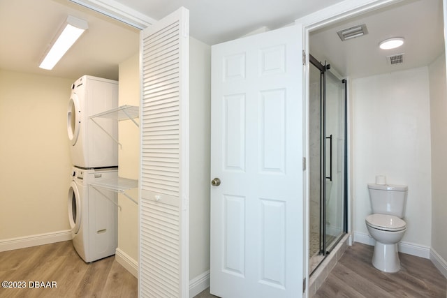 interior space with hardwood / wood-style flooring, stacked washer / dryer, and toilet