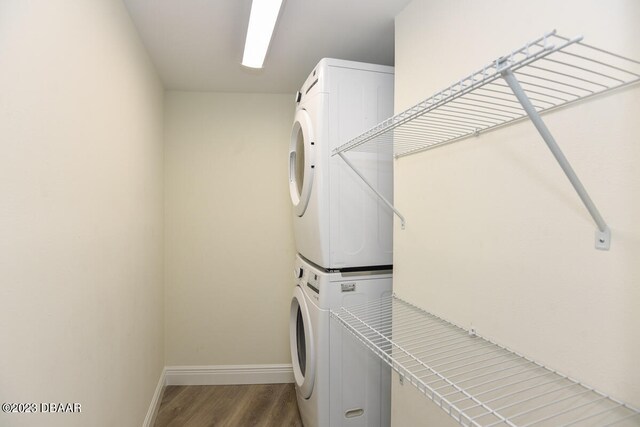 clothes washing area featuring stacked washing maching and dryer and hardwood / wood-style flooring