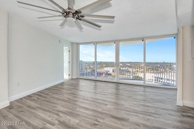 unfurnished room featuring ceiling fan, floor to ceiling windows, and light hardwood / wood-style floors