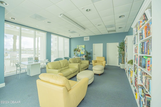 living room with a drop ceiling and dark carpet