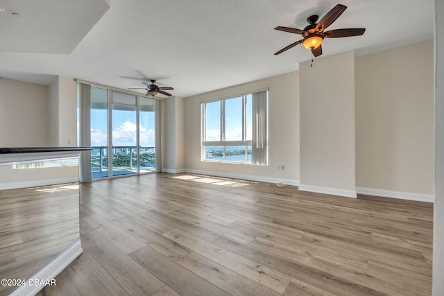 unfurnished living room featuring ceiling fan, a textured ceiling, and light hardwood / wood-style floors