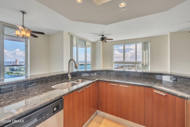 kitchen featuring dark stone counters, sink, dishwasher, a water view, and ceiling fan