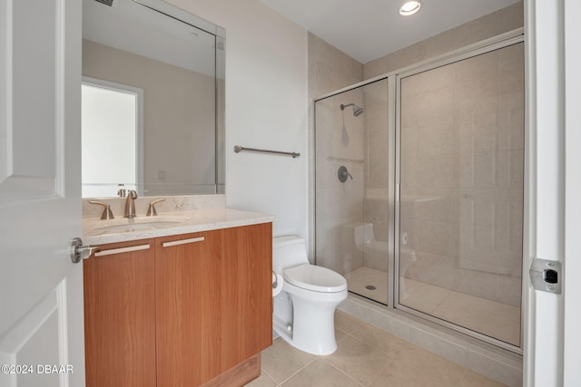 bathroom featuring toilet, vanity, tile patterned floors, and a shower with shower door