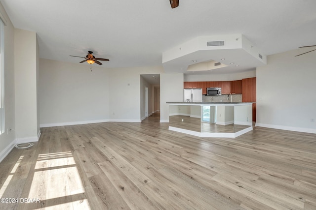 unfurnished living room with light hardwood / wood-style flooring, ceiling fan, and sink