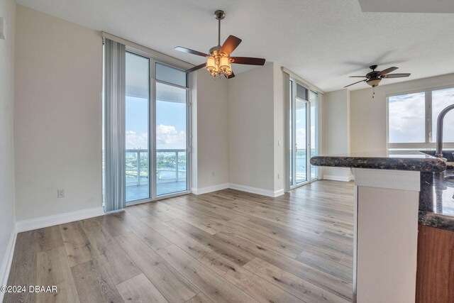 kitchen with light wood-type flooring, kitchen peninsula, a textured ceiling, and ceiling fan