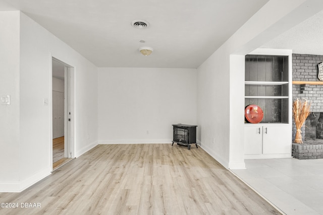 1703 Hill St, Edgewater, FL 32132 - spare room featuring a wood stove, a brick fireplace, and light hardwood / wood-style flooring