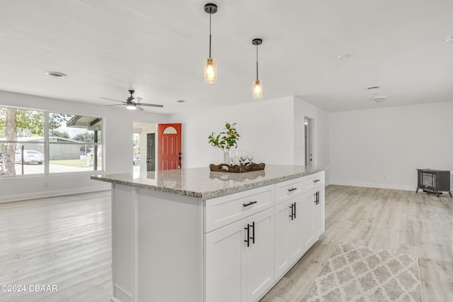 1703 Hill St, Edgewater, FL 32132 - kitchen featuring white cabinets, light hardwood / wood-style flooring, a center island, and light stone counters