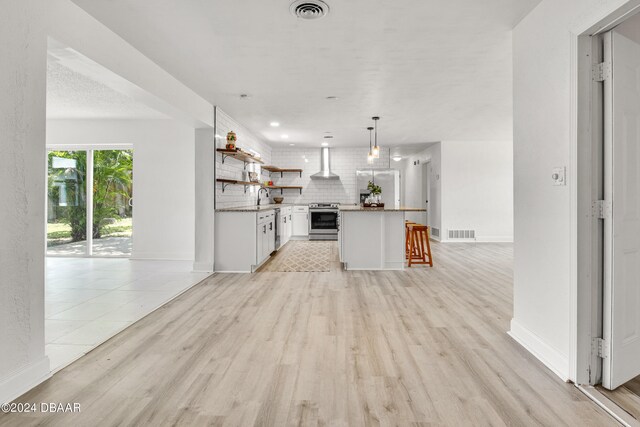 1703 Hill St, Edgewater, FL 32132 - kitchen featuring light wood-type flooring, white cabinetry, decorative light fixtures, wall chimney exhaust hood, and stainless steel electric stove