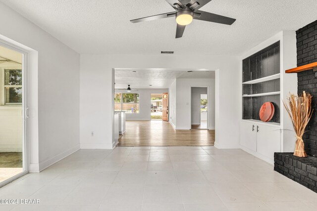 1703 Hill St, Edgewater, FL 32132 - interior space featuring built in shelves, a textured ceiling, ceiling fan, a fireplace, and light wood-type flooring
