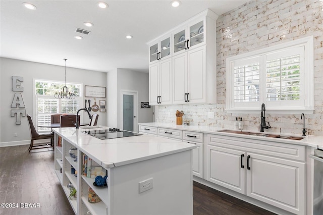 kitchen featuring white cabinets, a center island, pendant lighting, and black electric cooktop