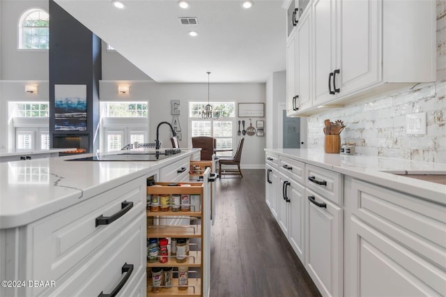 kitchen featuring white cabinets, a notable chandelier, backsplash, and hanging light fixtures