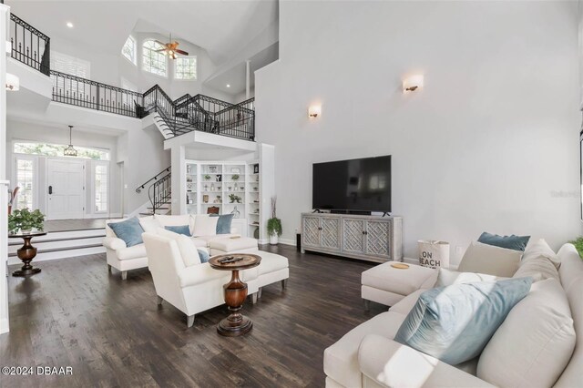 living room featuring a wealth of natural light, dark hardwood / wood-style flooring, a towering ceiling, and ceiling fan