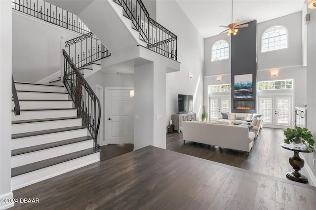 living room featuring dark hardwood / wood-style floors, ceiling fan, and a high ceiling