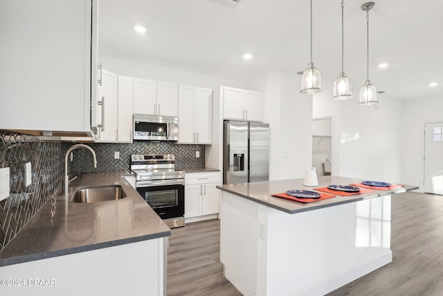 kitchen with white cabinets, a center island, stainless steel appliances, and hanging light fixtures