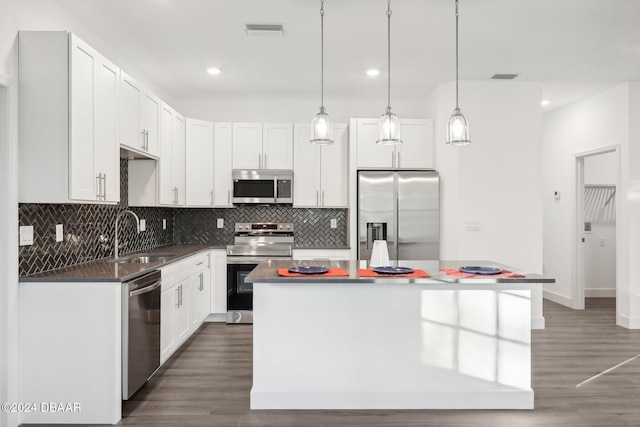 kitchen featuring white cabinets, appliances with stainless steel finishes, a kitchen island, and sink