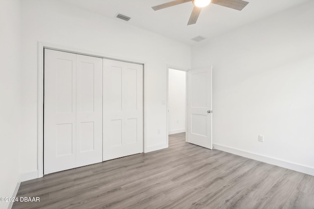 unfurnished bedroom with ceiling fan, light wood-type flooring, and a closet