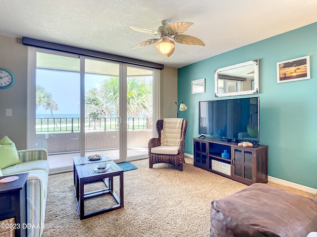 carpeted living room with ceiling fan and a textured ceiling