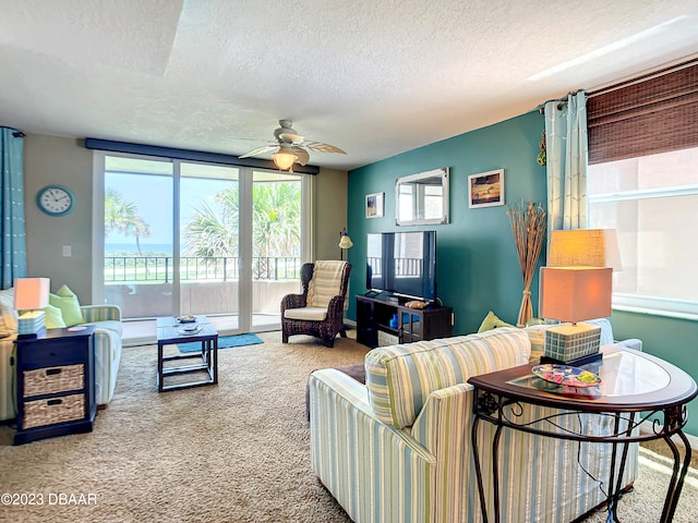 carpeted living room featuring ceiling fan and a textured ceiling