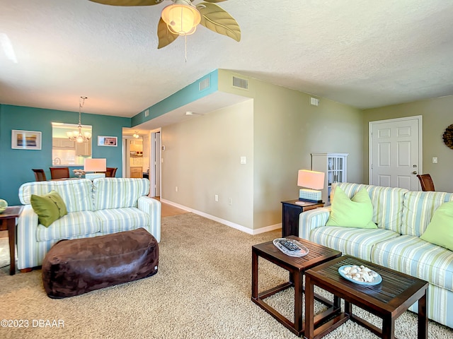 living room with ceiling fan with notable chandelier, light colored carpet, and a textured ceiling