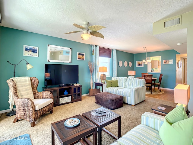 living room featuring a textured ceiling, hardwood / wood-style flooring, and ceiling fan with notable chandelier