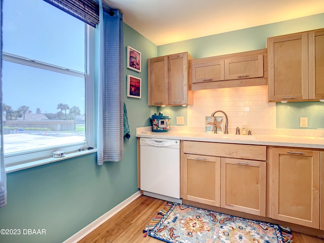 kitchen with sink, tasteful backsplash, light brown cabinetry, light hardwood / wood-style flooring, and dishwasher